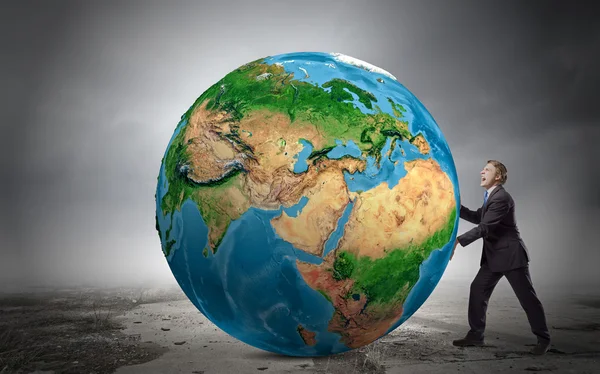 Businessman pushing big Earth planet — Stock Photo, Image