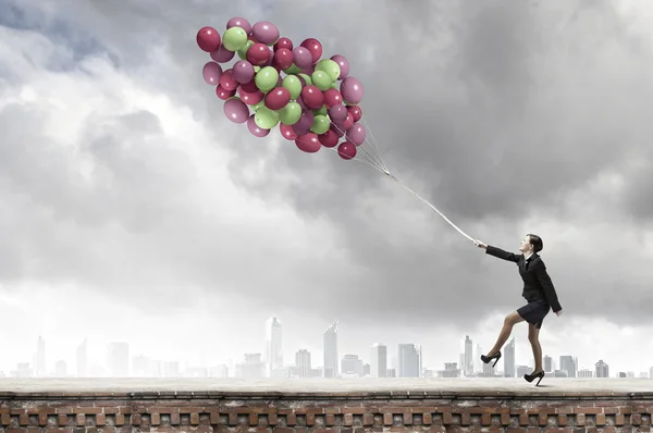 Geschäftsfrau läuft mit bunten Luftballons — Stockfoto