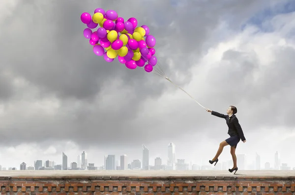 Businesswoman walking with bunch of colorful balloons — Stock Photo, Image