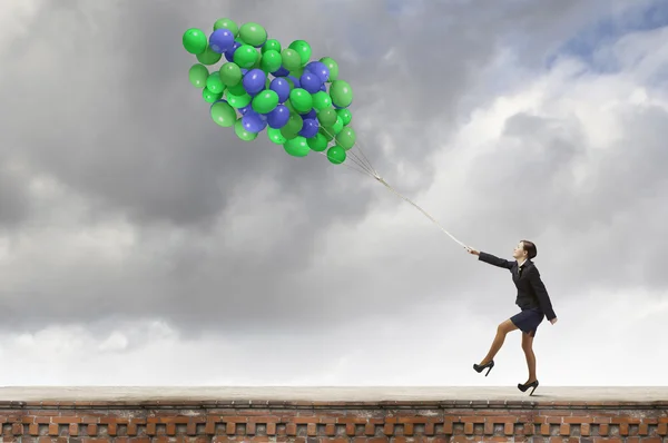 Mujer de negocios caminando con un montón de globos de colores —  Fotos de Stock