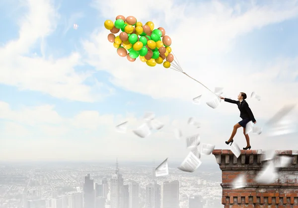 Mujer de negocios caminando con un montón de globos de colores — Foto de Stock