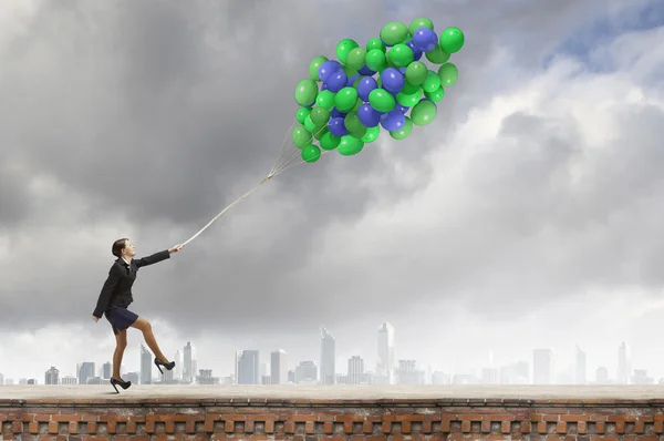 Empresária andando com um monte de balões coloridos Imagem De Stock