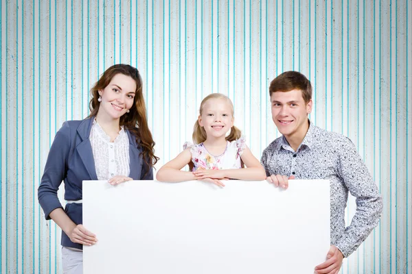 Família feliz segurando banner branco em branco — Fotografia de Stock