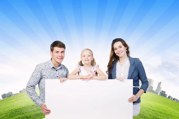 Família feliz segurando banner branco em branco — Fotografia de Stock