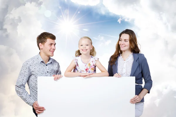 Família feliz segurando banner branco em branco — Fotografia de Stock