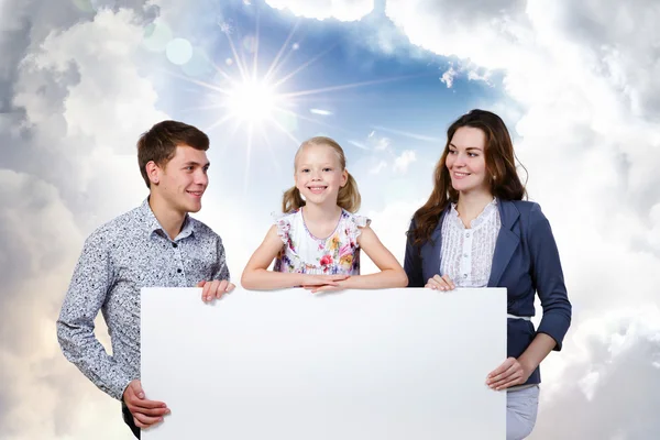 Família feliz segurando banner branco em branco — Fotografia de Stock