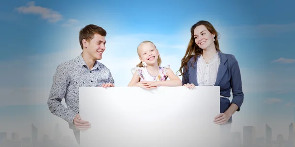 Happy family holding white blank banner — Stock Photo, Image