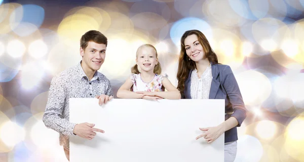 Happy family holding white blank banner — Stock Photo, Image