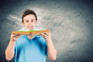 Adam açık bir kitap tutuyor.