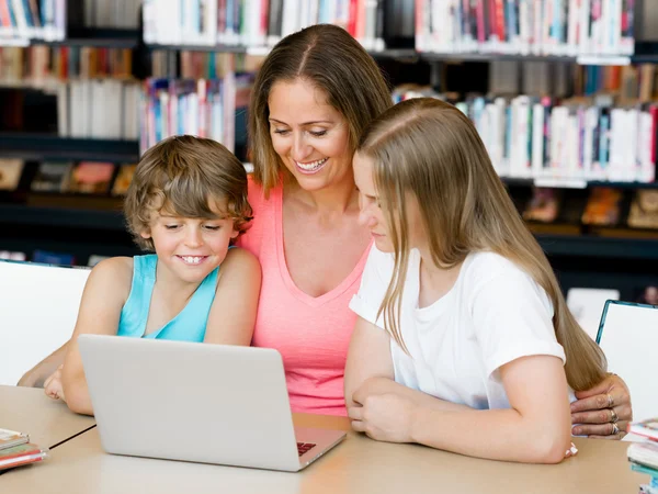 Moeder met kinderen in bibliotheek — Stockfoto