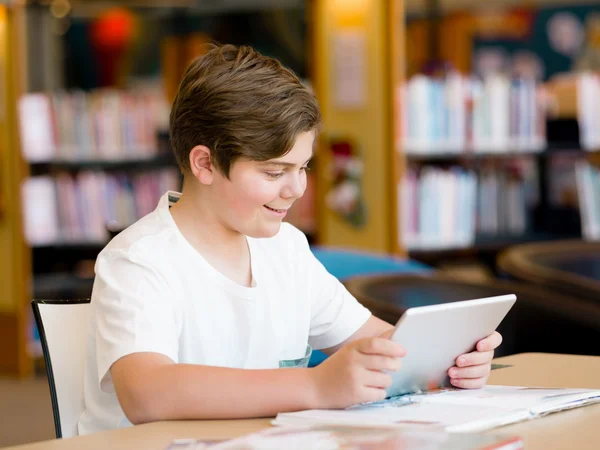 Teenage boy with tablet in library — Stock Photo, Image