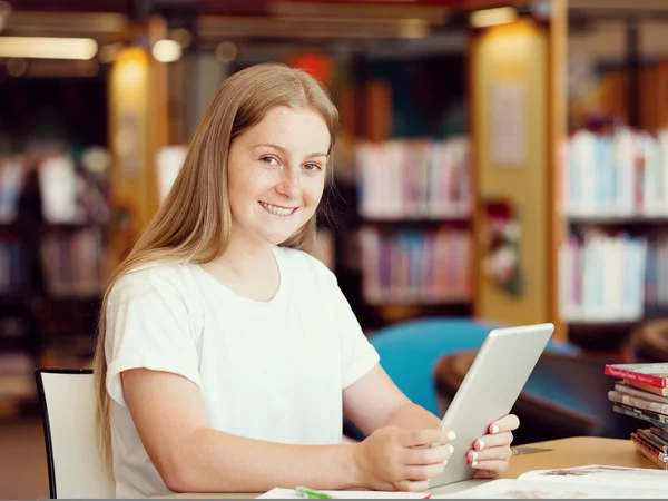 Ragazza adolescente con tablet in biblioteca — Foto Stock