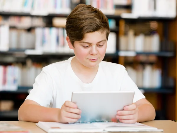 十几岁的男孩在图书馆中的平板电脑 — 图库照片