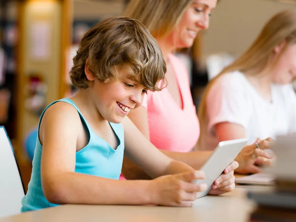 Jongen in bibliotheek met computer Rechtenvrije Stockfoto's