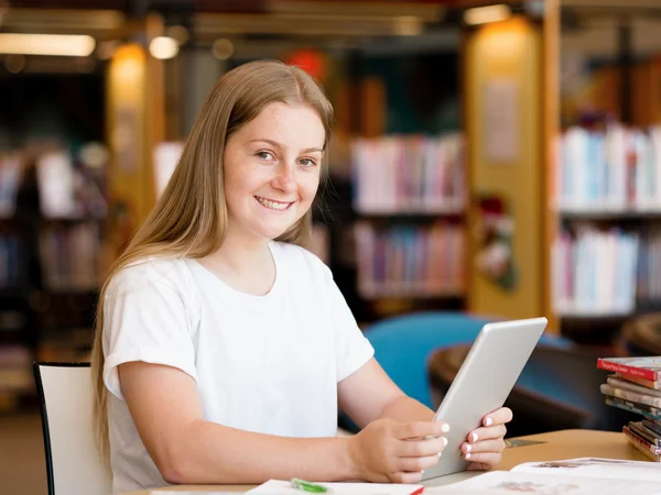 Dospívající dívka s tablet v knihovně — Stock fotografie