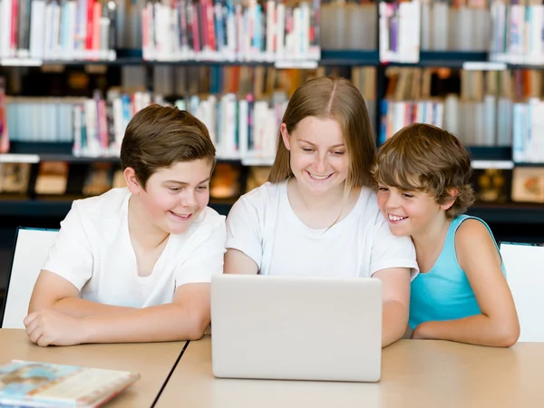 Drie kinderen in bibliotheek — Stockfoto