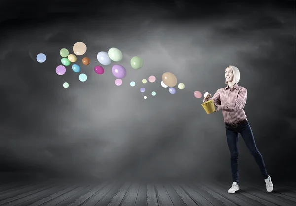 Girl splashing balloons from bucket — Stok fotoğraf