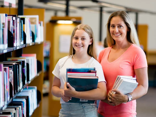 Meisje en haar moeder in bibliotheek — Stockfoto