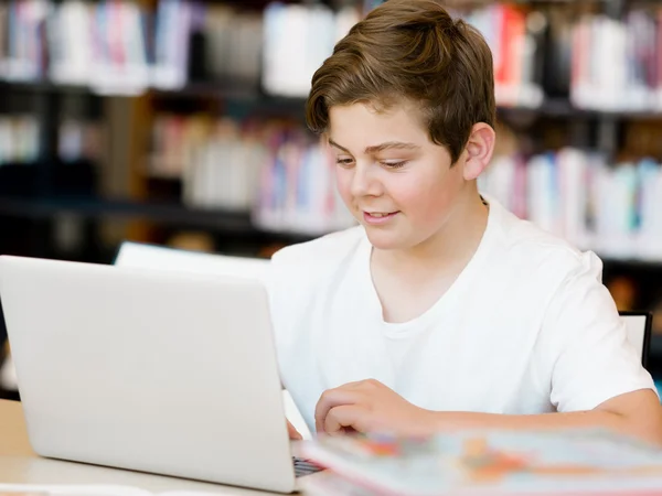 Teenage boy with tablet in library — Stock Photo, Image