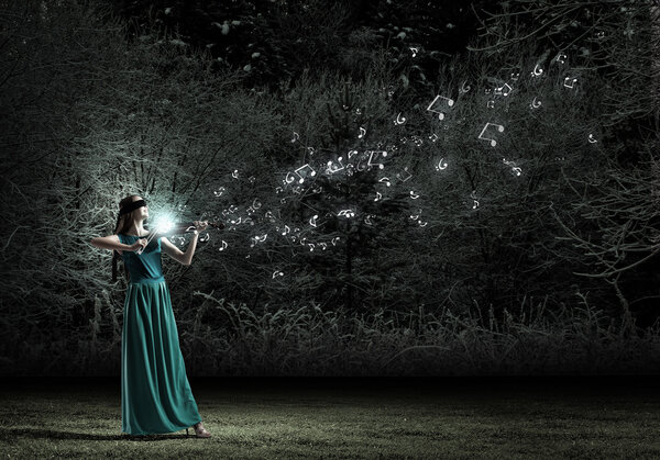Attractive woman in long green dress playing violin