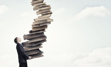 Adam elinde kitap yığını ile
