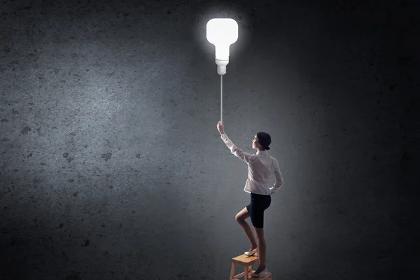 Businesswoman reaching light bulb — Stock Photo, Image