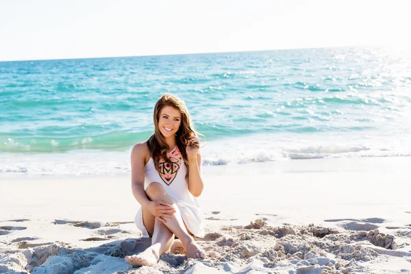 Jonge vrouw zittend op het strand — Stockfoto