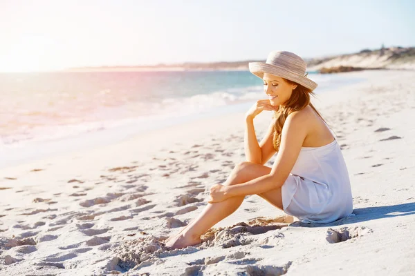 Ung kvinna sitter på stranden — Stockfoto