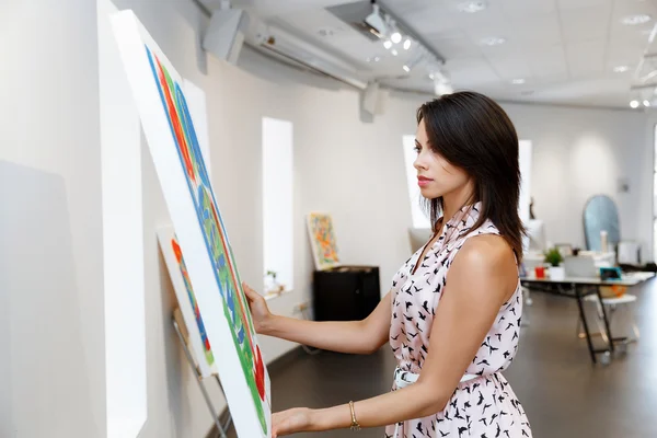 Jeune femme caucasienne debout dans la galerie d'art devant des peintures — Photo