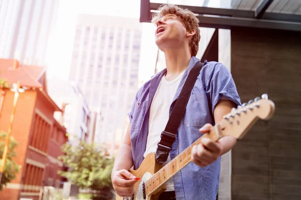 Jovem músico com guitarra na cidade — Fotografia de Stock