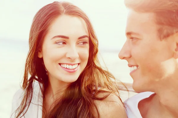 Romantische jonge paar zittend op het strand — Stockfoto