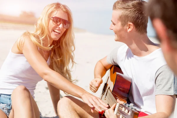 Schöne junge Leute mit Gitarre am Strand — Stockfoto