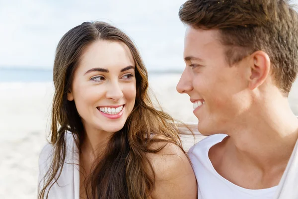 Romántica pareja joven sentada en la playa — Foto de Stock