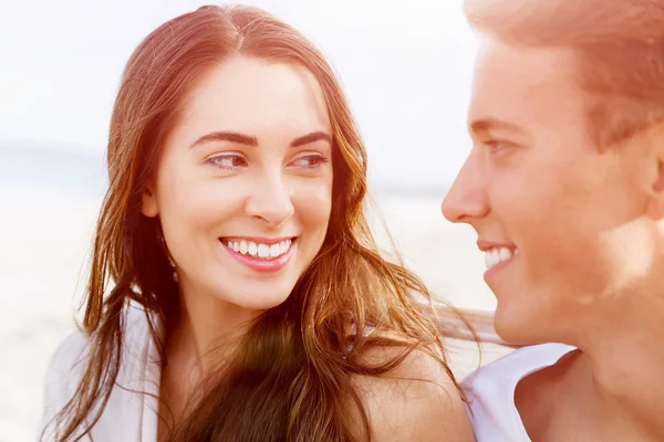 Romantische jonge paar zittend op het strand — Stockfoto