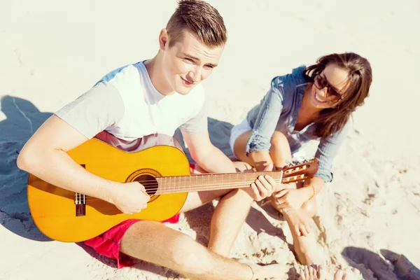 Jovens bonitos com guitarra na praia — Fotografia de Stock
