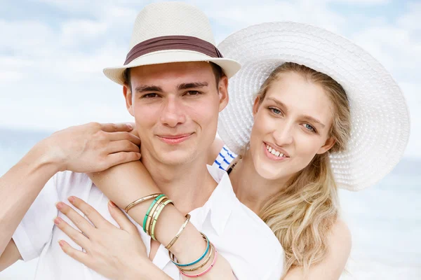 Romantische jonge paar zittend op het strand — Stockfoto