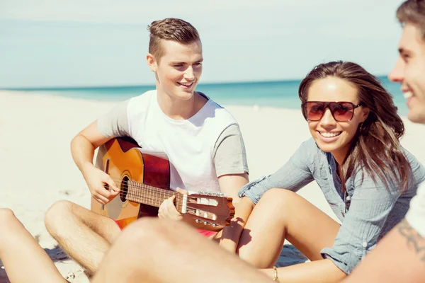 Jovens bonitos com guitarra na praia — Fotografia de Stock