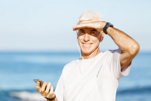 Male runner with his mobile smart phone standing outdoors Royalty Free Stock Images