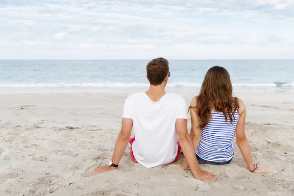 Romantiska unga paret sitter på stranden — Stockfoto