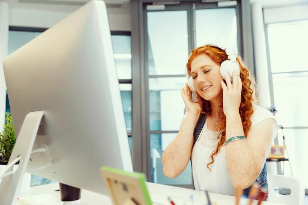 Mujer joven con auriculares trabajando en la oficina — Foto de Stock