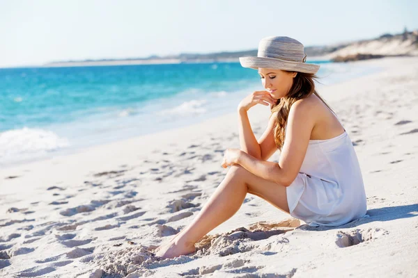 Mujer joven sentada en la playa — Foto de Stock