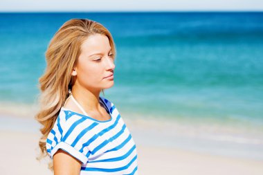 Genç bir kadın sahilde dinleniyor.