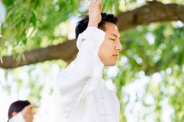 Yakışıklı adam Thai Chi yapıyor.