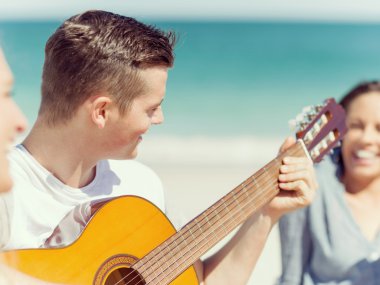 Genç adam sahilde gitar çalmak