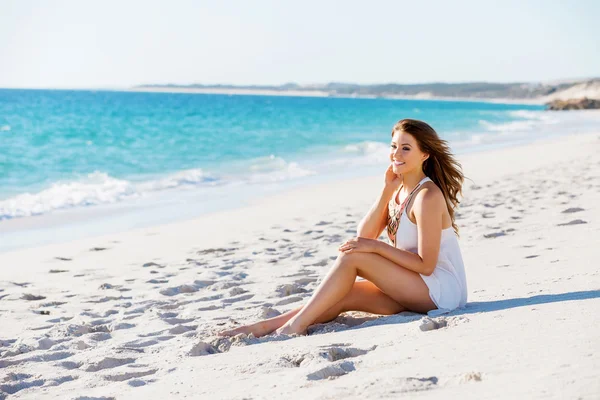 Fiatal nő ül a strandon — Stock Fotó