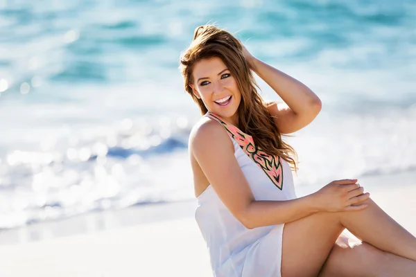 Jonge vrouw zittend op het strand — Stockfoto