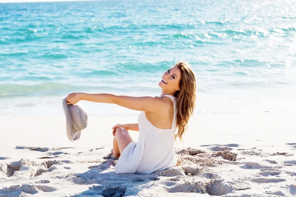 Jonge vrouw zittend op het strand — Stockfoto