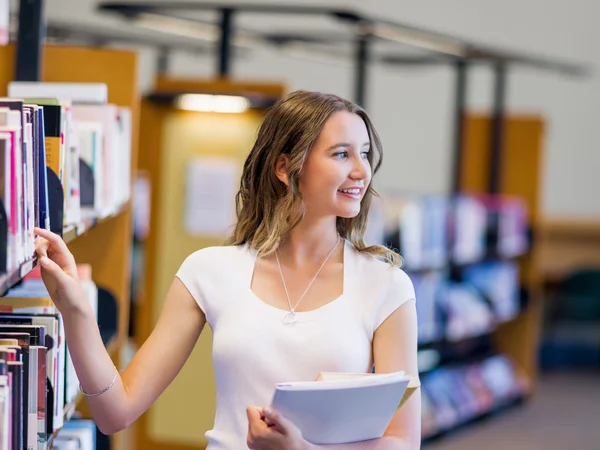 Gelukkig vrouwelijke student houden van boeken in de bibliotheek — Stockfoto