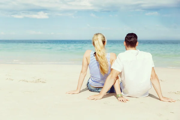 Romántica pareja joven sentada en la playa — Foto de Stock