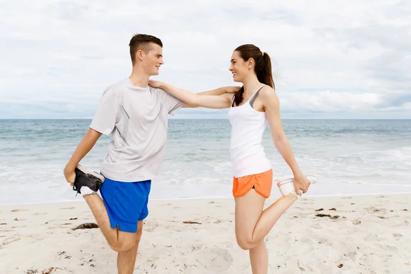 Des coureurs. Jeune couple exerçant et stertching sur la plage — Photo